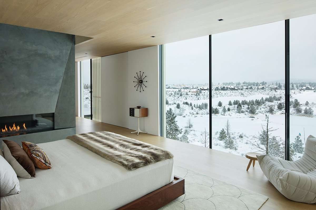 Bedroom with fireplace overlooking snowy landscape