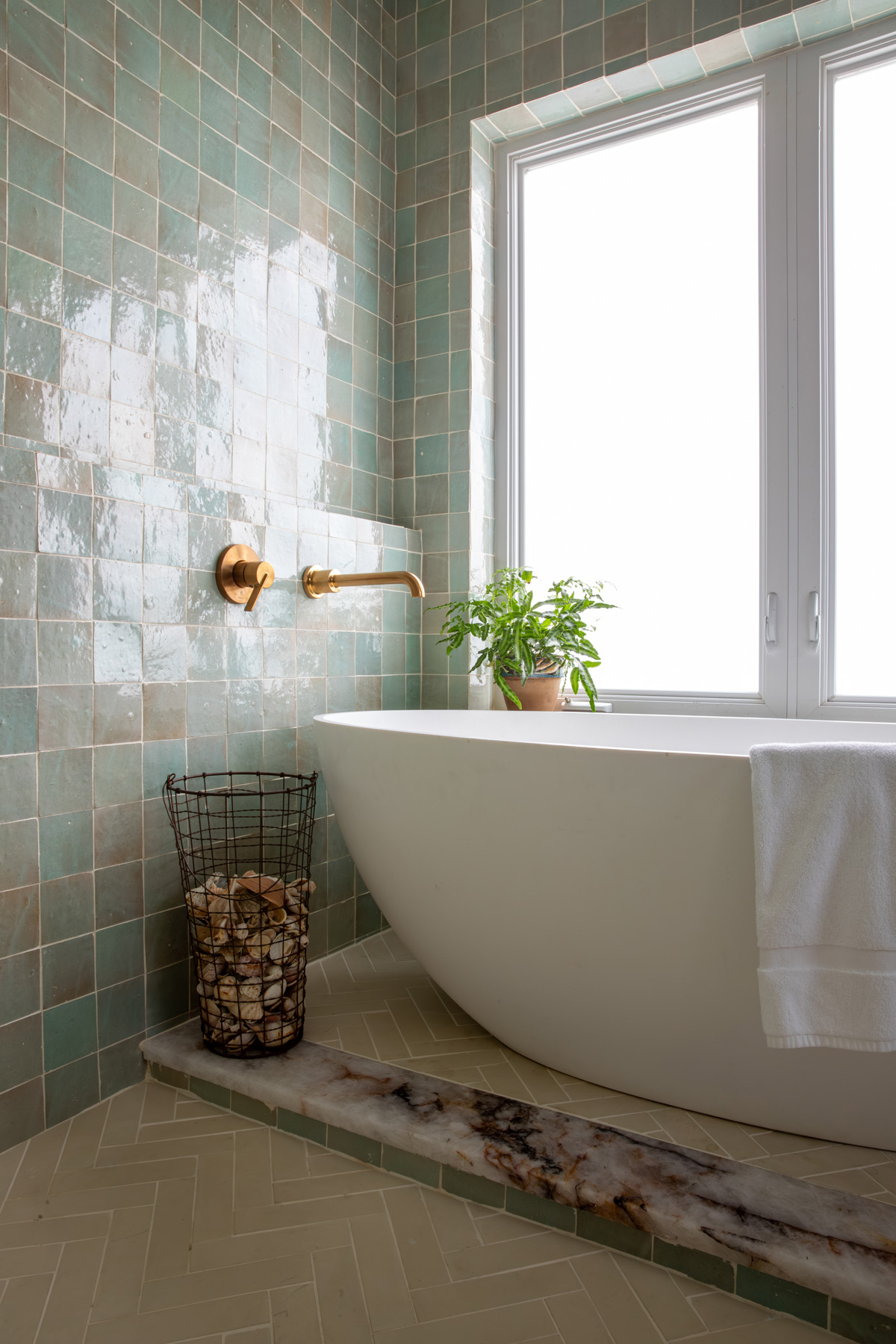 White bath tub with green tile wall and gold fixtures