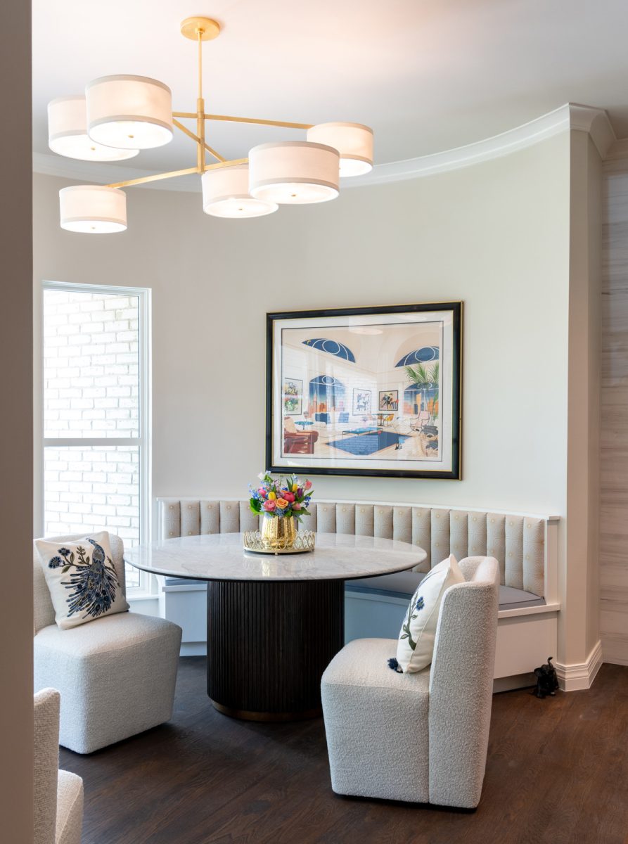 Small dining area with round table, upholstered chairs, and a modern chandelier.